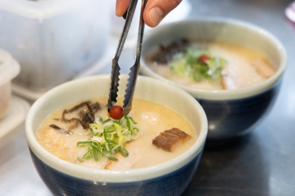 一般のラーメンと異なるスタイルは、修業経験のない先代が考案した。丸みのある丼はスープが冷めない形と厚み。美人画の口紅をイメージした小梅がアクセントになっている。